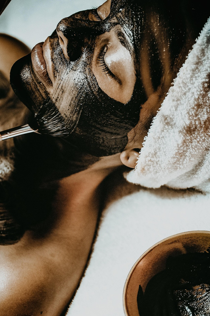 Woman laying down having a black face mask applied. 
